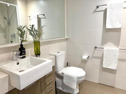 a white bathroom with a sink and a toilet at Modern 2B1B Apt Southbank Next to Crown W Parking in Melbourne