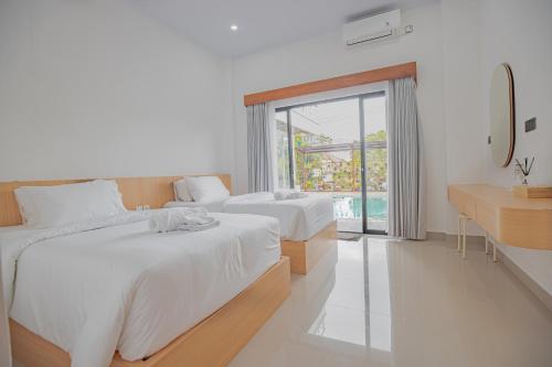 two beds in a white room with a window at Habitat Boutique Dive Resort in Tulamben