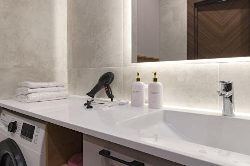 a bathroom counter with a sink and a washing machine at GreenLine Atmosfera luxe 2 bedroom apartment in Zhezdi