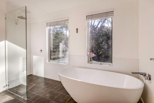 baño con bañera blanca y ventanas en Anelga - Beachfront on Eagle Bay, en Dunsborough