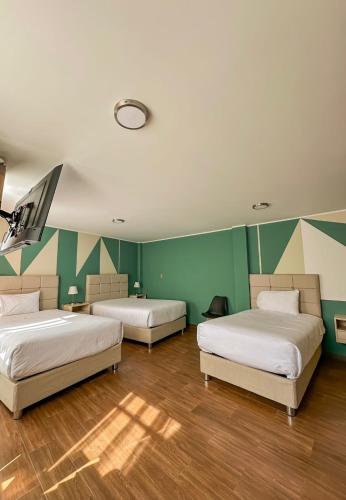 two beds in a room with green walls and wooden floors at Andari Hoteles in Arequipa