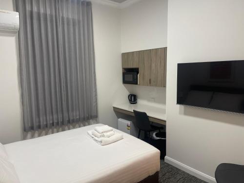 a hotel room with a bed and a desk and a tv at Costello Hotels Port Augusta in Port Augusta