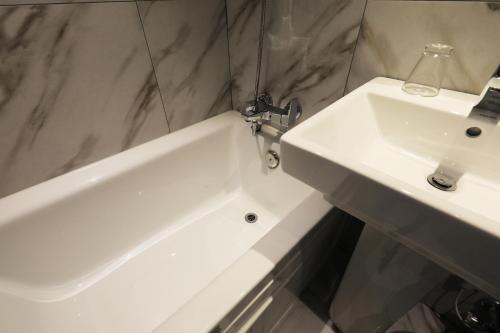 a bathroom with a sink and a white bath tub at Sindang Rainbow Hotel in Seoul