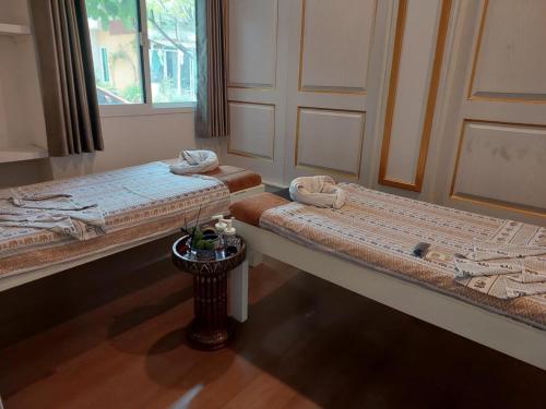 two beds sitting in a room with a table at Ln House Chiang Mai in Chiang Mai