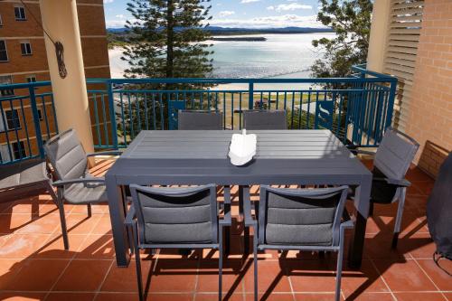 a table and chairs on a balcony with a view of the ocean at Whitesands 402 in Forster