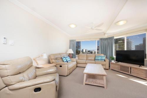 a living room with white furniture and a flat screen tv at Whitesands 402 in Forster