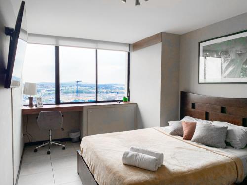 a bedroom with a bed with a desk and windows at Depa Puerto Santana,AC,WIFI,Bares,Restaurante,segurida 24-7 in Guayaquil