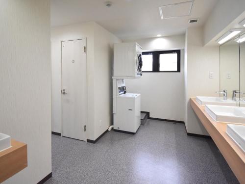 a bathroom with two sinks and a white refrigerator at HOTEL WINDS ASAKUSA Capsule Inn 浅草 in Tokyo