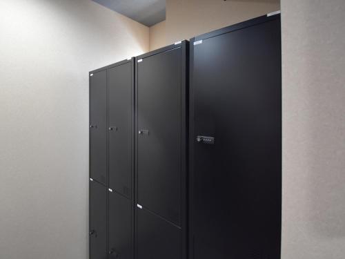 a row of black lockers in a room at HOTEL WINDS ASAKUSA Capsule Inn 浅草 in Tokyo