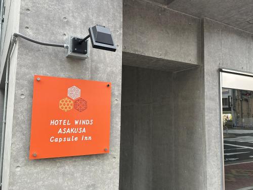 a sign on the side of a building with a camera at HOTEL WINDS ASAKUSA Capsule Inn 浅草 in Tokyo