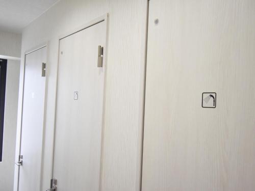 a row of doors in a room with a mirror at HOTEL WINDS ASAKUSA Capsule Inn 浅草 in Tokyo