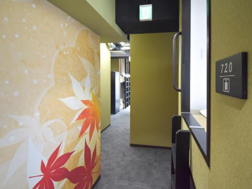 a hallway with a painting of a woman on a wall at HOTEL WINDS ASAKUSA Capsule Inn 浅草 in Tokyo