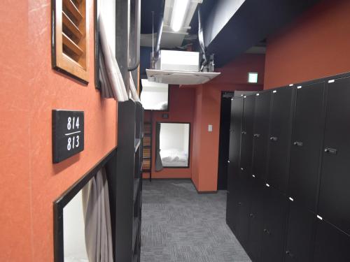 a locker room with black lockers and a bed at HOTEL WINDS ASAKUSA Capsule Inn 浅草 in Tokyo