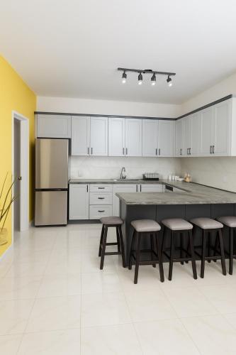 a kitchen with white cabinets and a large island with stools at Villa Amor in Korçë