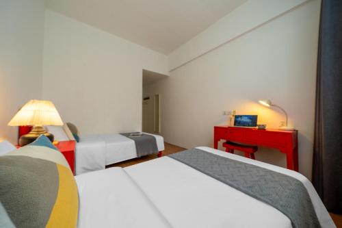 a hotel room with three beds and a red desk at Peking Youth Hostel in Beijing