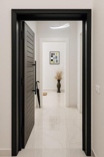 a hallway with a black door and a tile floor at Villa Amor in Korçë