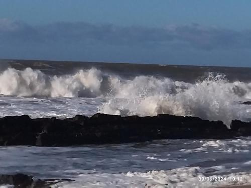a large wave in the ocean near a pier at Hospedaje La Tuna in Rocha
