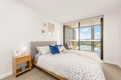 ein Schlafzimmer mit einem Bett mit blauen Kissen und einem Fenster in der Unterkunft Dickson Stylish 2BR Retreat w Views n Parking in Downer