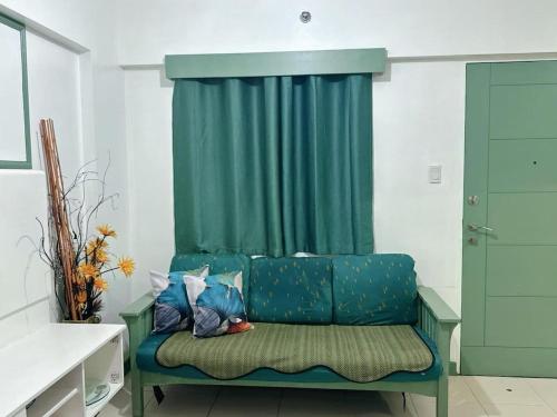 a green couch in a room with a green curtain at Apartment in Parañaque in Manila