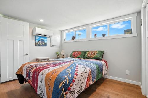 a bedroom with a bed with a colorful comforter and windows at The Fluffy Cow - BRAND NEW 1 BD CABIN in Custer