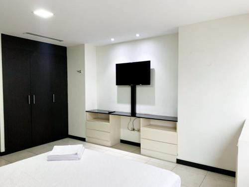 a bedroom with a bed and a tv on the wall at Depa Puerto Santana,AC,WIFI,Bares,Restaurante,segurida 24-7 in Guayaquil