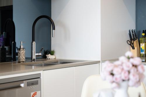 eine Küche mit einem Waschbecken und einer Vase aus Blumen in der Unterkunft Cozy Lyneham Retreat, Views, Gym n Free Parking in Downer