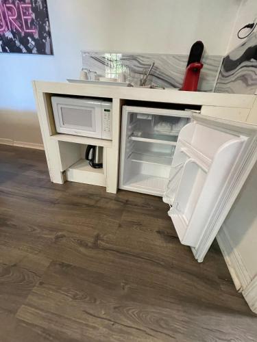an open cabinet with an open refrigerator and microwave at Little Carnation in St. Augustine