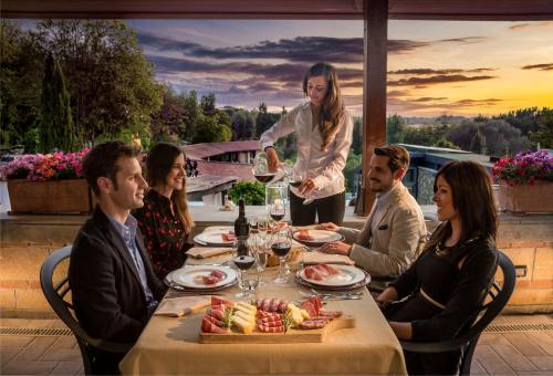 a group of people sitting around a table with a woman pouring wine at Villa Hotel Valle Del Marta Resort in Tarquinia