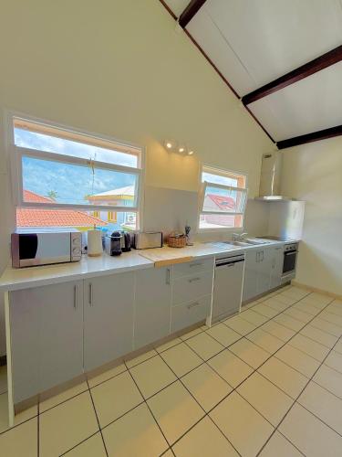 a large kitchen with white cabinets and a window at La Case bourbon in Sainte-Anne