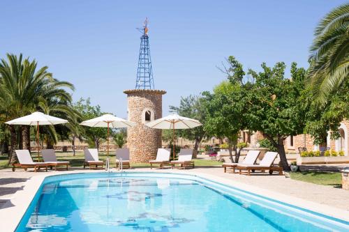 einen Pool mit Stühlen und Sonnenschirmen sowie einen Turm in der Unterkunft Agroturismo Es Quatre Cantons in Binissalem