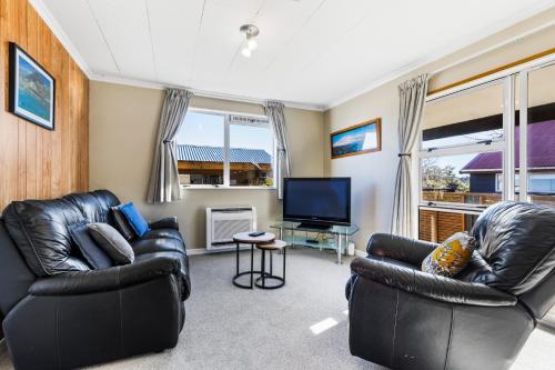 a living room with two leather chairs and a flat screen tv at All Year Round Adventure Base - National Park in National Park