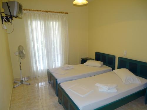 a bedroom with two beds and a window with a fan at Flokos in Lygia