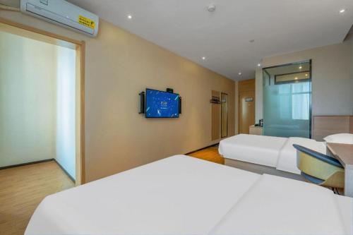 a bedroom with two beds and a tv on the wall at IU Hotels Xinzhou Bus Terminal in Xinzhou