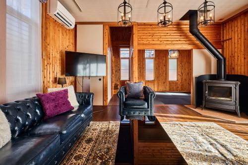 a living room with a black leather couch and a stove at -Light House- 那須中心エリアの道の駅から徒歩圏内で那須塩原駅からバスでも行ける完全プライベート貸切ログハウス in Nasu-yumoto