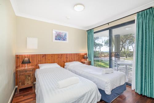 Dos camas en una habitación con balcón. en 98 Steps to the Beach 2BR Coastal Getaway, en Broadwater
