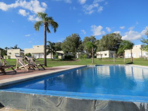 a swimming pool with two chairs and a palm tree at Bungalows Mexico in Concepción del Uruguay