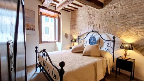 1 dormitorio con 1 cama en una habitación con una pared de ladrillo en Saxa Suite - Dimore nel Tempo, en Perugia