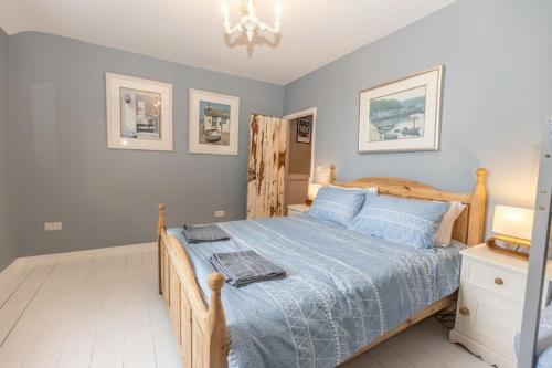 a bedroom with a wooden bed with a blue comforter at Cozy Cottage, Wrington in Wrington