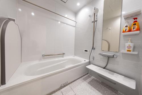 a white bathroom with a tub and a sink at theView 三浦市晴海町 in Miura