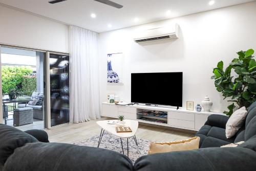 un soggiorno con divano e TV a schermo piatto di Aura Luxe Family Stay a Berrimah