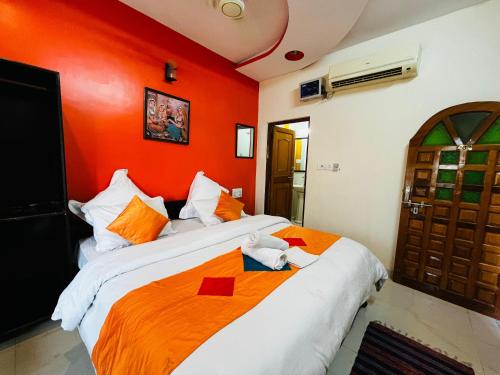 two beds in a room with an orange wall at Golden Marigold Hotel in Jaisalmer