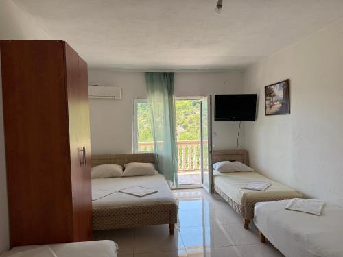 a room with two beds and a tv and a window at Villa Djekovic in Čanj