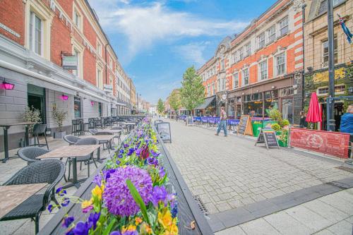a city street with tables and flowers and buildings at Oxford Street Accommodation in Southampton