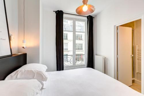 une chambre avec un lit blanc et une fenêtre dans l'établissement Habitat Parisien - Drouot Luxe, à Paris