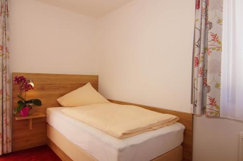 a small bedroom with a white bed and a table at Gasthaus und Landhotel Wiedmann in Eresing