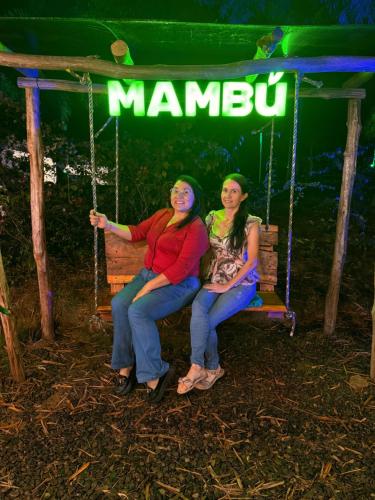 two women sitting on a swing with a sign that says manneau at Villas del bambú in San Gil