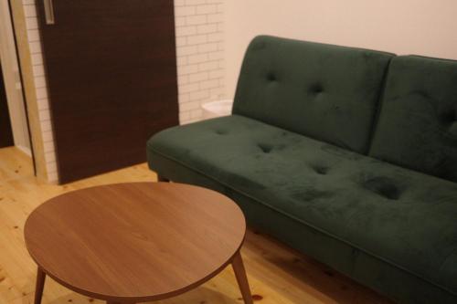 a living room with a green couch and a table at 住之江駐車場付きCozy Family House in Osaka