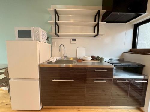 a kitchen with a white refrigerator and a sink at 住之江駐車場付きCozy Family House in Osaka