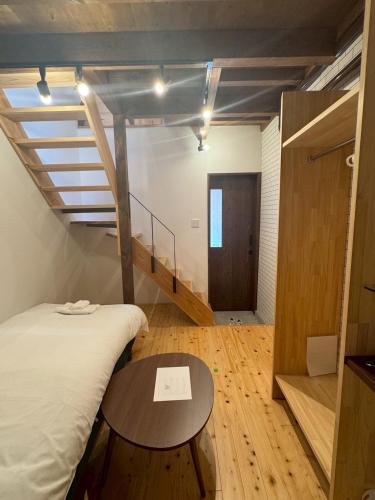 a room with a bed and a table and a staircase at 住之江駐車場付きCozy Family House in Osaka