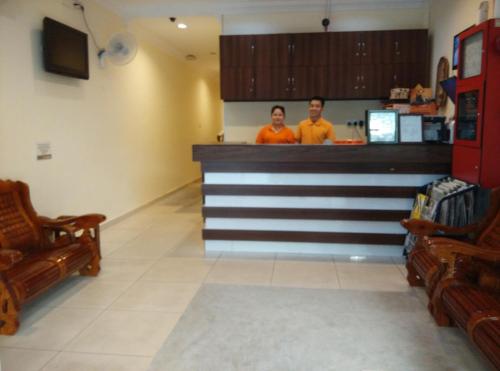 two people standing at a bar in a restaurant at Hotel Traveller in Kota Kinabalu